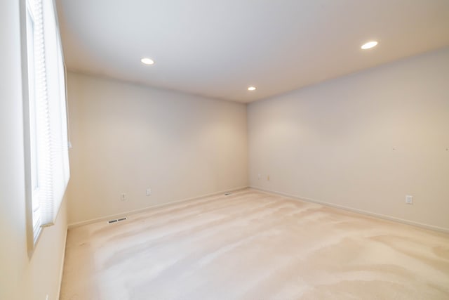 empty room with light colored carpet, recessed lighting, and baseboards