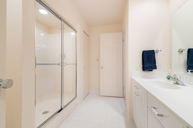 full bath with a stall shower, vanity, tile patterned flooring, and baseboards