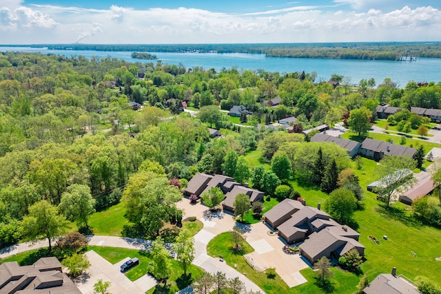 aerial perspective of suburban area featuring a large body of water and a forest