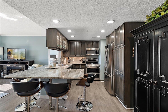 143 Campau Cir NW Unit 1616, Grand Rapids, MI 49503 - kitchen with appliances with stainless steel finishes, a sink, light wood-type flooring, a breakfast bar, and a peninsula