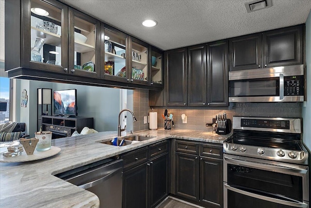143 Campau Cir NW Unit 1616, Grand Rapids, MI 49503 - kitchen featuring stainless steel appliances, a sink, tasteful backsplash, glass insert cabinets, and light stone countertops