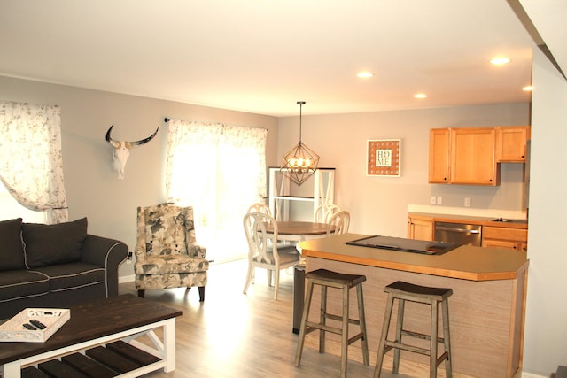 kitchen with light brown cabinetry, stainless steel dishwasher, a kitchen breakfast bar, black electric cooktop, and recessed lighting