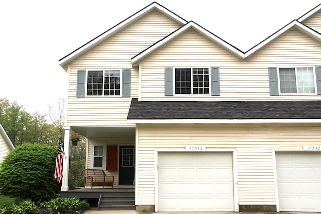 view of front of home with covered porch, a garage, and roof with shingles