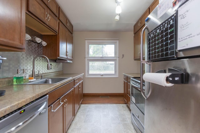 1609 Sheridan Ave, Niles, MI 49120 - kitchen featuring appliances with stainless steel finishes, a sink, backsplash, baseboards, and brown cabinets