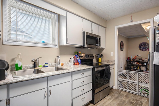 238-240 W Division St, Sparta, MI 49345 - kitchen with appliances with stainless steel finishes, light wood-style flooring, a sink, light countertops, and white cabinetry