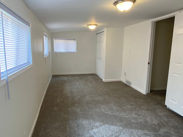 empty room featuring dark carpet and baseboards