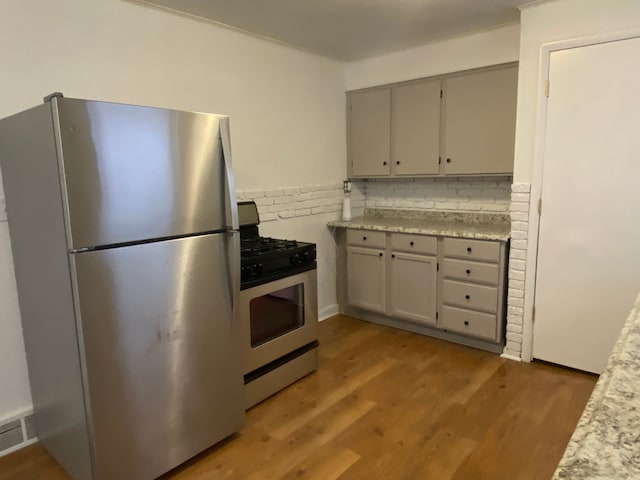 kitchen with stainless steel appliances, wood finished floors, light countertops, and gray cabinetry