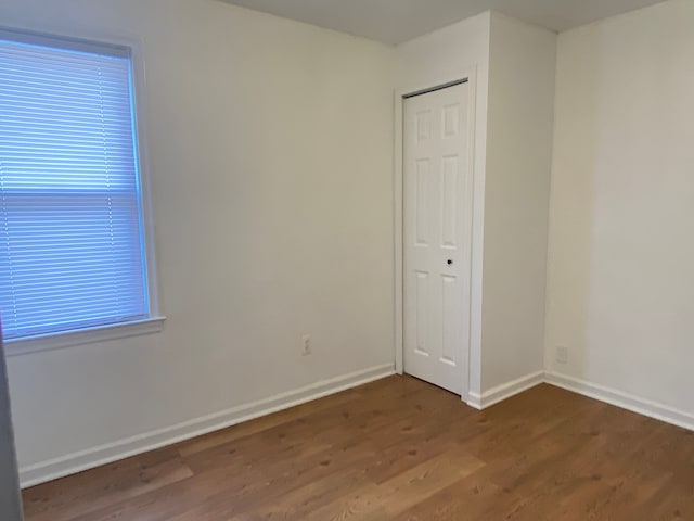 empty room with dark wood-style flooring and baseboards
