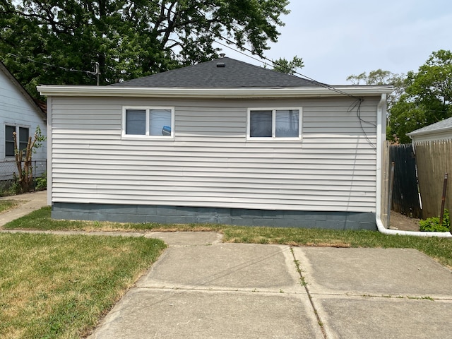 view of home's exterior featuring fence, a shingled roof, and a patio
