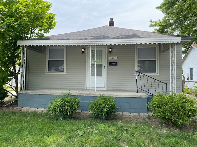 view of front of home with a porch, a chimney, and a shingled roof