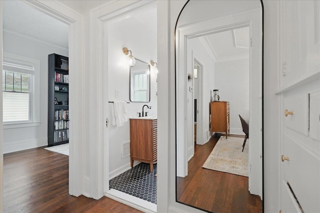 hall featuring crown molding, dark wood finished floors, plenty of natural light, and baseboards