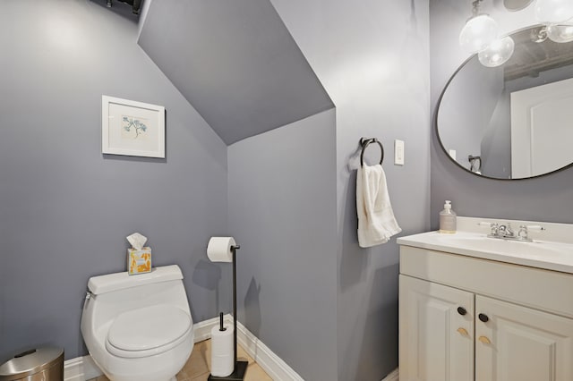 bathroom with toilet, vanity, baseboards, and lofted ceiling