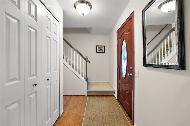 entrance foyer featuring light wood finished floors, stairs, and baseboards
