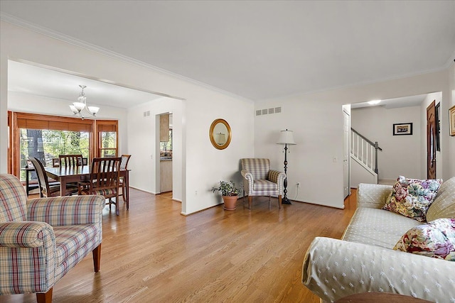 living room with a chandelier, light wood-type flooring, ornamental molding, stairway, and baseboards