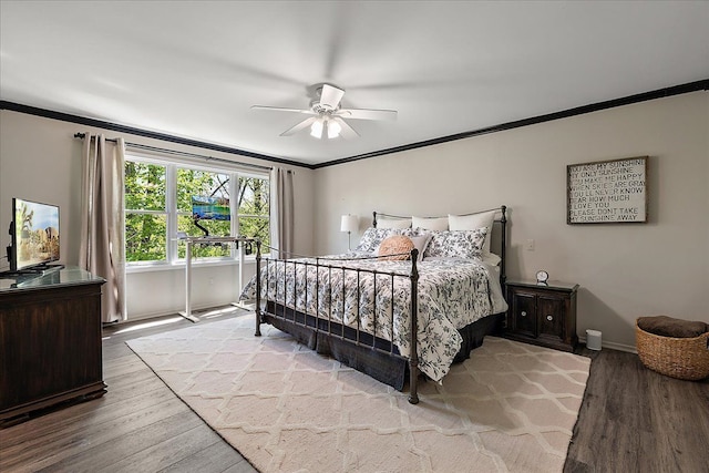 bedroom featuring ornamental molding, wood finished floors, baseboards, and a ceiling fan