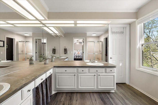 full bath featuring wood finished floors, a shower stall, double vanity, plenty of natural light, and ornamental molding