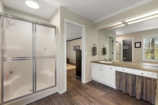 bathroom with wood finished floors, a shower stall, vanity, baseboards, and ornamental molding