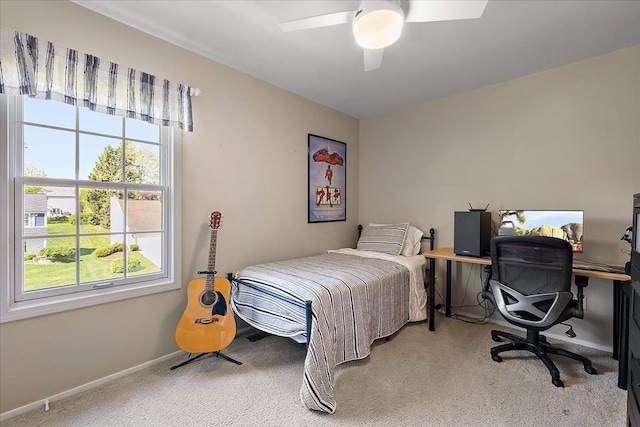 carpeted bedroom featuring multiple windows, baseboards, a ceiling fan, and a desk