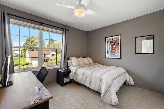 bedroom featuring light colored carpet, baseboards, a desk, and a ceiling fan