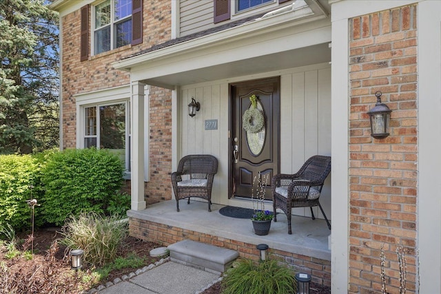 view of exterior entry featuring covered porch and brick siding