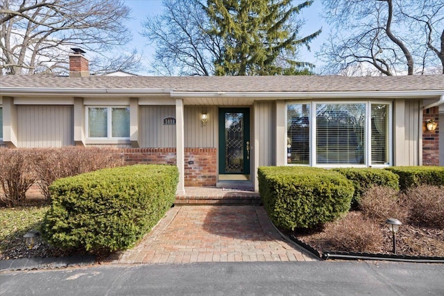 5080 Kitson Ln, West Bloomfield, MI 48324 - doorway to property with brick siding, a chimney, and roof with shingles