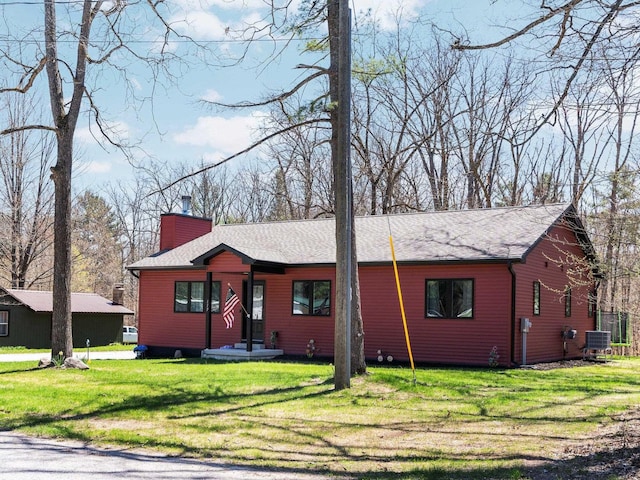 119 Maple St, Fife Lake, MI 49633 - view of front of house featuring a chimney, a front lawn, and central air condition unit