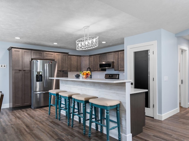 119 Maple St, Fife Lake, MI 49633 - kitchen featuring appliances with stainless steel finishes, dark brown cabinets, dark wood-style floors, baseboards, and light countertops
