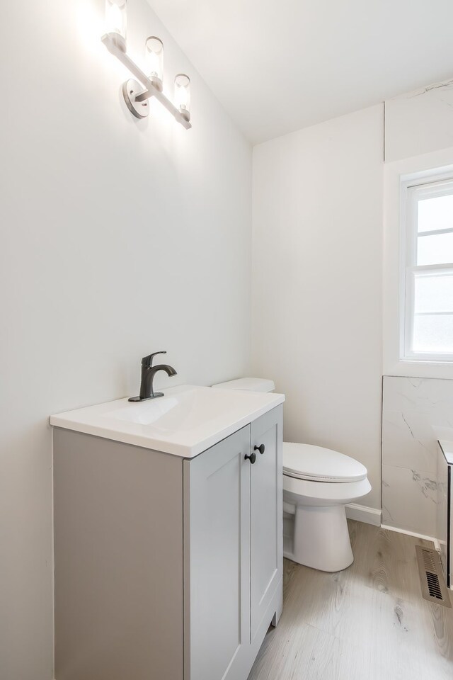 8345 Pontiac Lake Rd, White Lake, MI 48386 - bathroom featuring vanity, toilet, wood finished floors, and baseboards