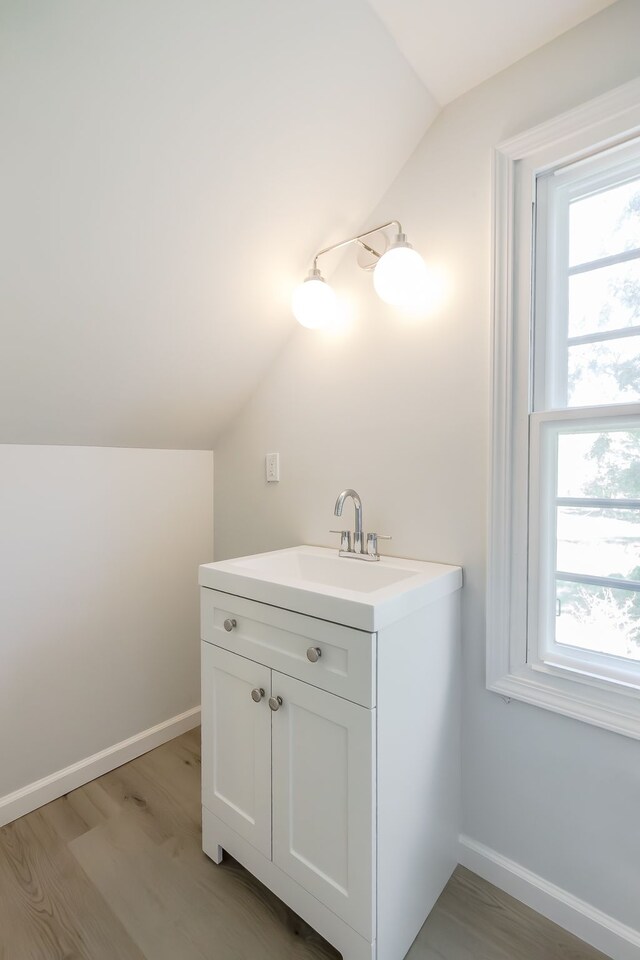 8345 Pontiac Lake Rd, White Lake, MI 48386 - bathroom featuring vaulted ceiling, healthy amount of natural light, wood finished floors, baseboards, and vanity