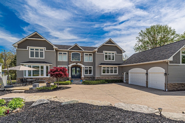 view of front of house with concrete driveway, a garage, stone siding, and a shingled roof