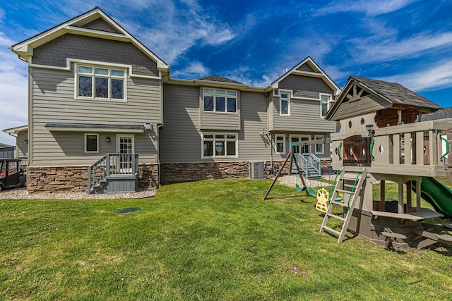 rear view of house featuring a playground, stone siding, and a yard