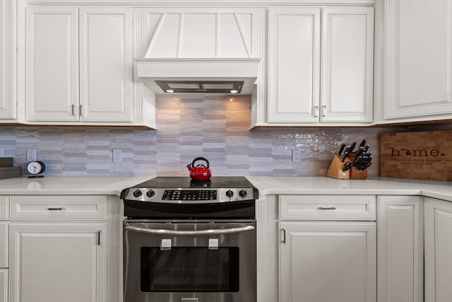 kitchen featuring stainless steel electric stove, custom range hood, white cabinets, light countertops, and tasteful backsplash