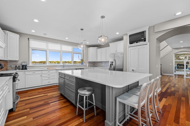 kitchen featuring appliances with stainless steel finishes, white cabinets, a kitchen island, decorative backsplash, and recessed lighting