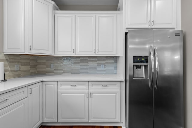 kitchen with stainless steel fridge, white cabinets, and decorative backsplash
