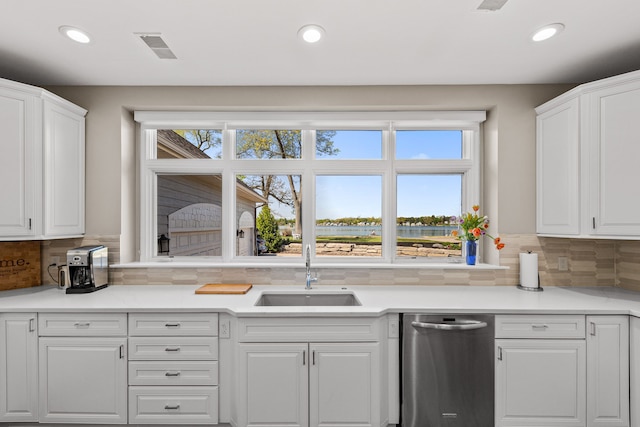 kitchen with stainless steel dishwasher, a sink, plenty of natural light, white cabinets, and recessed lighting