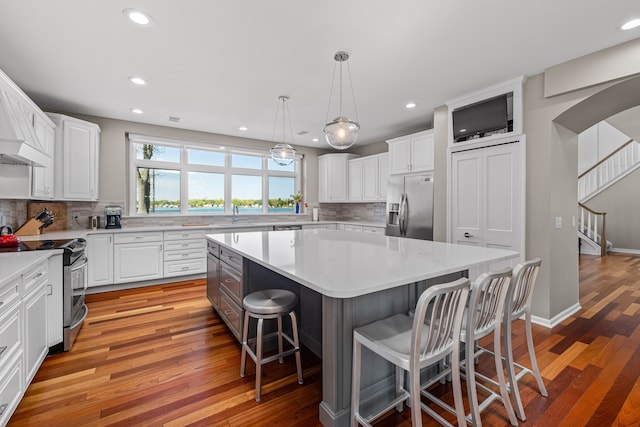 kitchen with stainless steel appliances, light wood-style floors, a breakfast bar area, backsplash, and recessed lighting