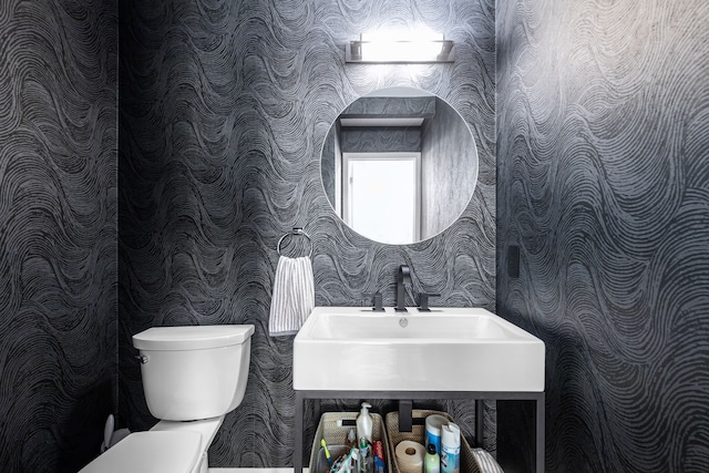 bathroom featuring wallpapered walls, toilet, and a sink