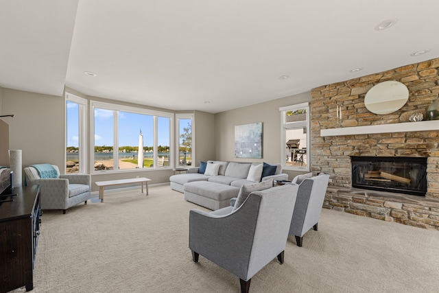 living area with carpet floors, healthy amount of natural light, and a stone fireplace