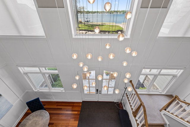 foyer entrance with a decorative wall, wood finished floors, stairs, a skylight, and a water view