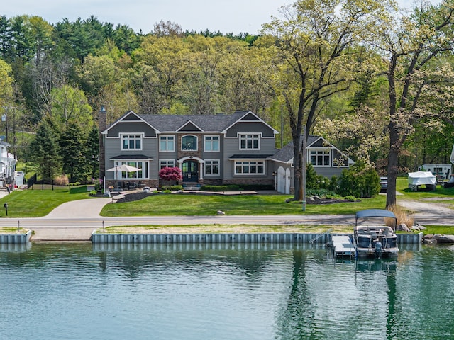 back of house featuring a water view and a lawn