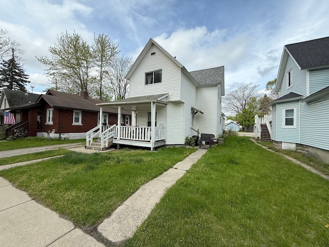 1917 16th St, Port Huron, MI 48060 - traditional-style house with covered porch, a front lawn, and a shingled roof