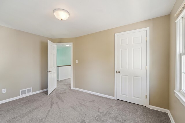 unfurnished bedroom featuring carpet flooring, baseboards, and multiple windows