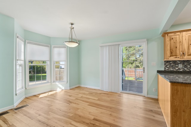 unfurnished dining area with light wood-style floors and baseboards