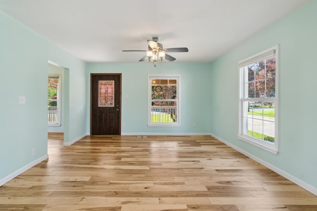 entrance foyer with ceiling fan, healthy amount of natural light, light wood-style flooring, and baseboards
