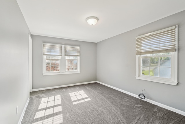 spare room with carpet, plenty of natural light, and baseboards