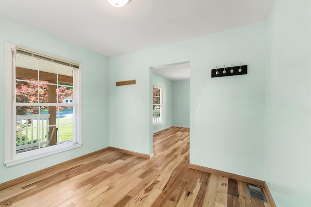 unfurnished room with light wood finished floors, healthy amount of natural light, and baseboards