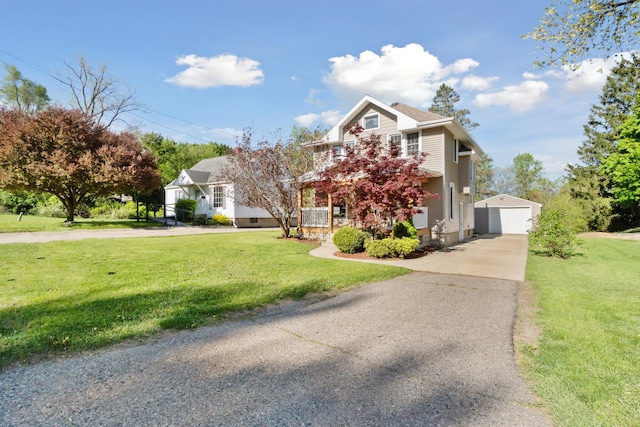 view of front facade with driveway, an outdoor structure, a front yard, and a detached garage