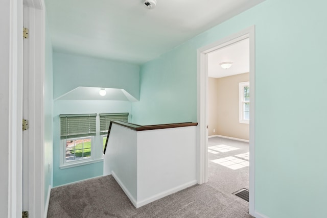 hall featuring an upstairs landing, carpet, and baseboards