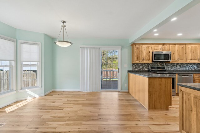 kitchen with stainless steel appliances, light wood-style floors, backsplash, baseboards, and pendant lighting