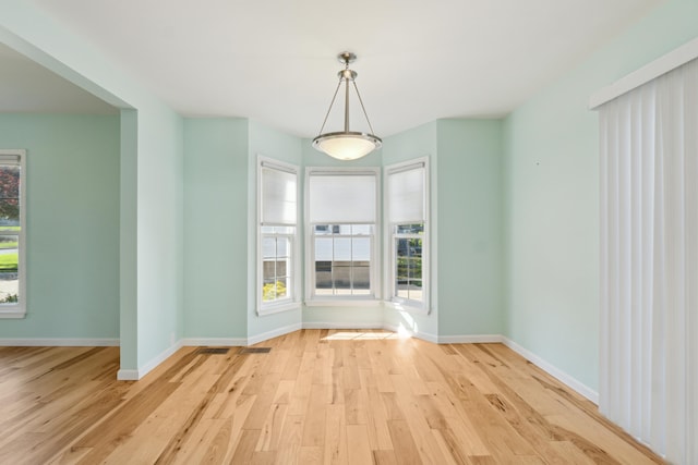 unfurnished dining area with light wood finished floors and baseboards